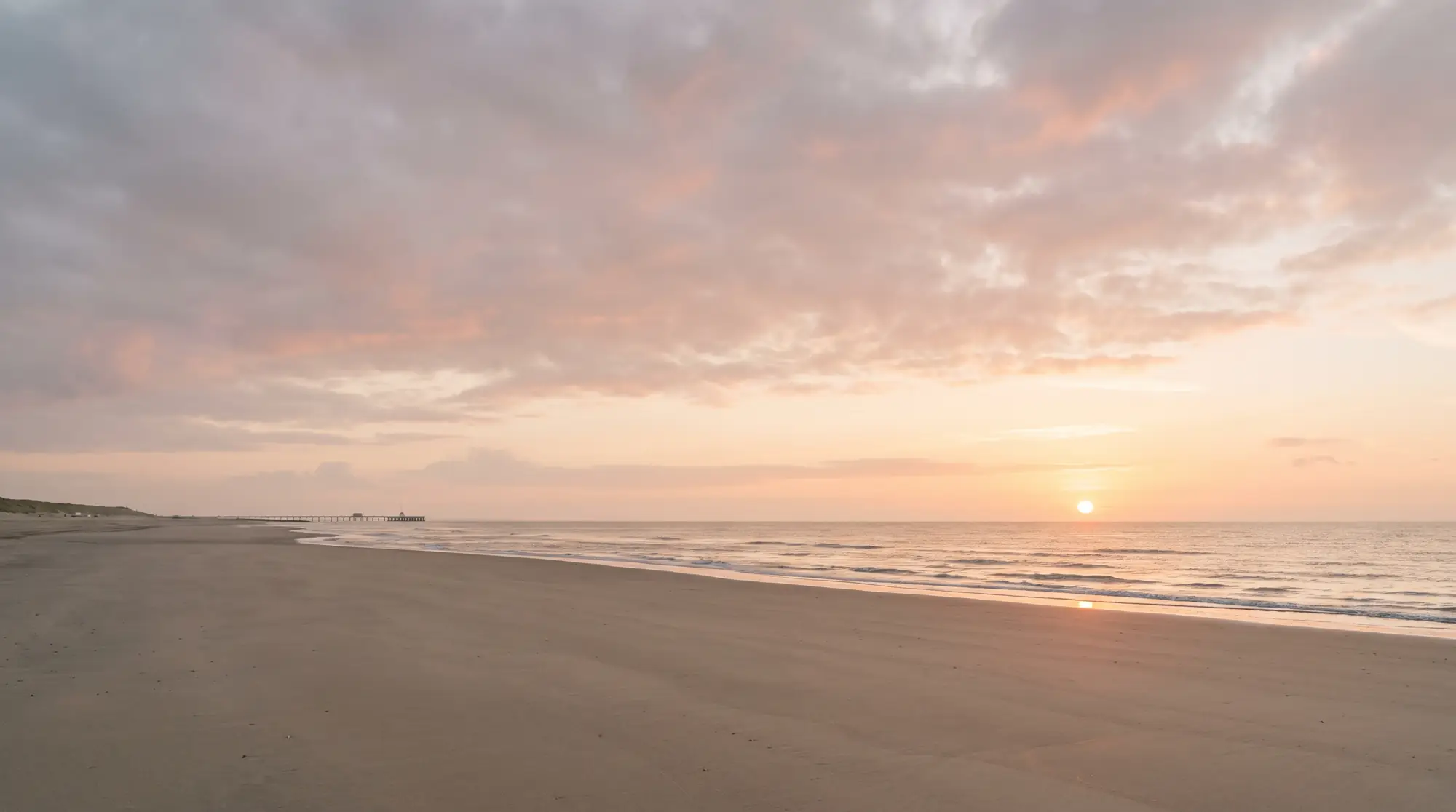 The Lincolnshire coast at Skegness at sunrise, a calm sea and an empty beach